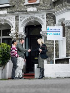 couple meets with realtor in front of a property for sale