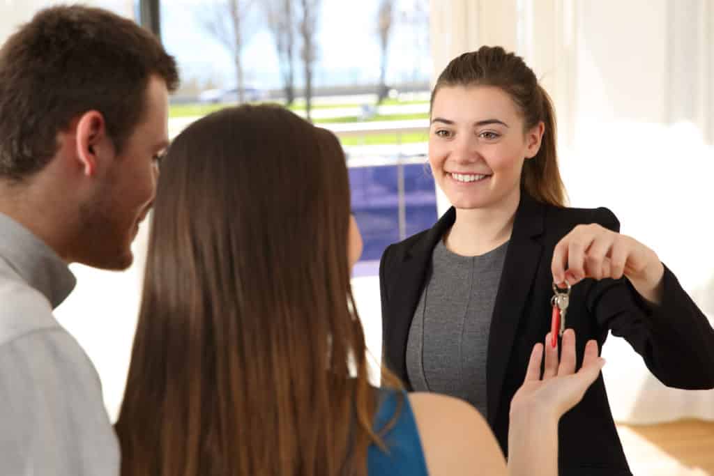 landlord smiles and offers keys to tenants