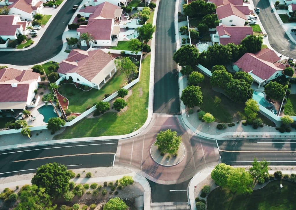 a neighborhood of red-roofed suburban homes shown from above shows the state of the real estate market