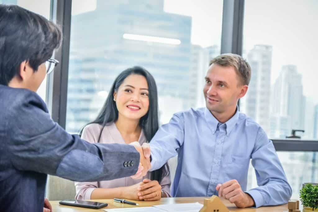 Couple shaking hands with property manager after buying a home