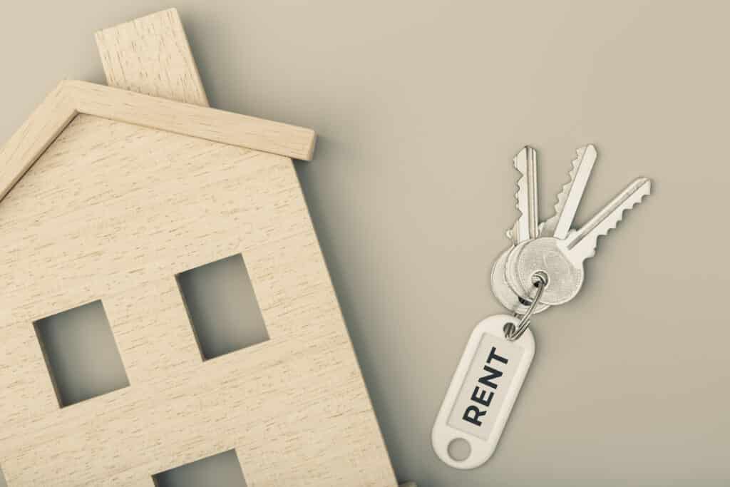 rental keys laying on a surface with a small wooden model house