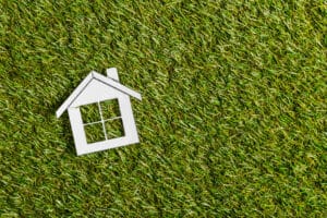 top view of white paper house on green grass, energy efficient home concept