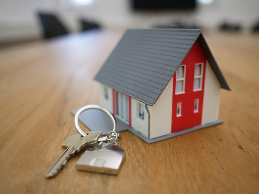 A small fake house with keys placed next to it on a table