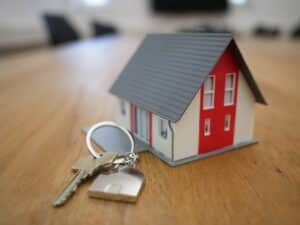 A small fake house with keys placed next to it on a table