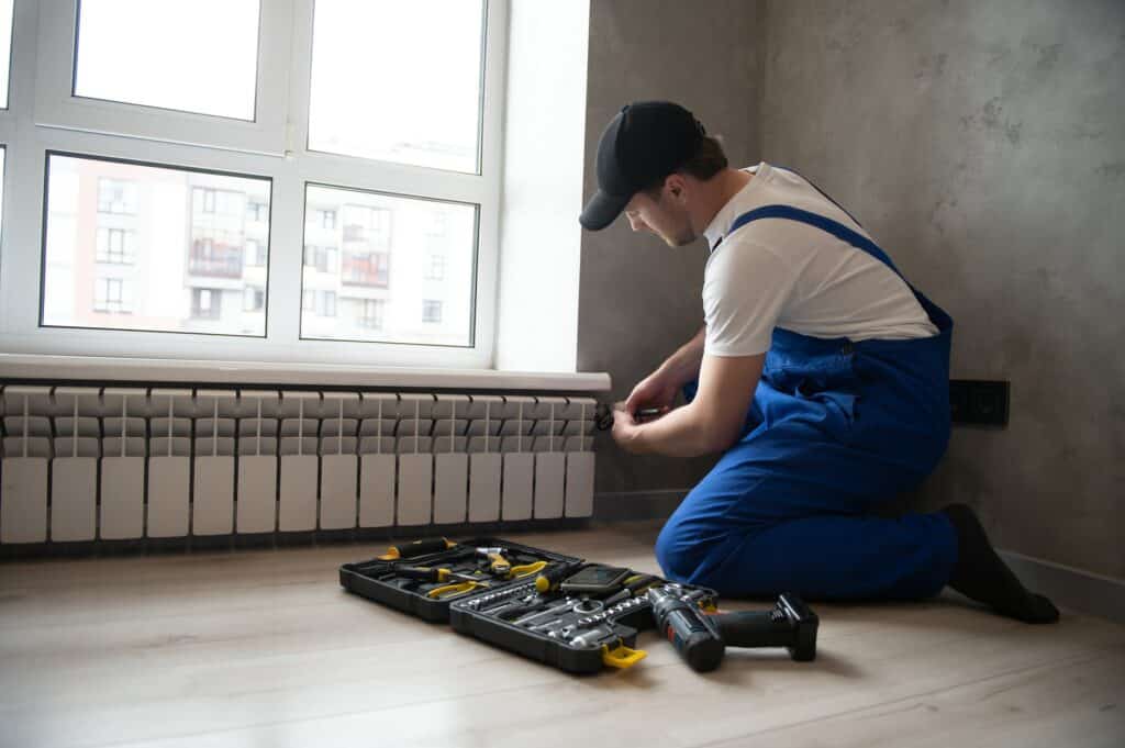 contractor installing a heating unit under a window