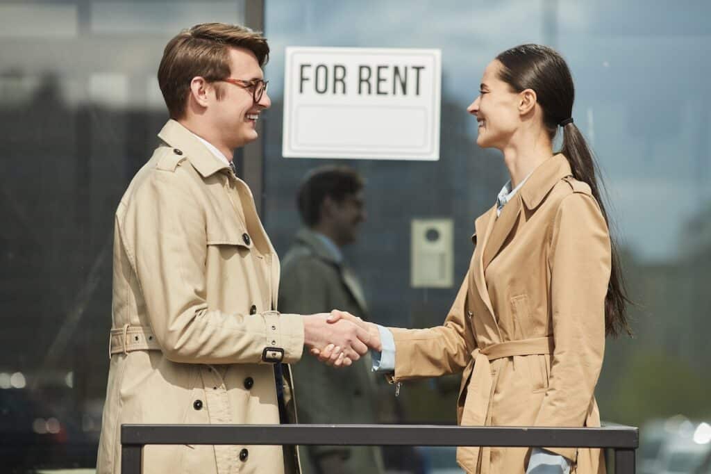 Man and woman shaking hands outside a business for rent
